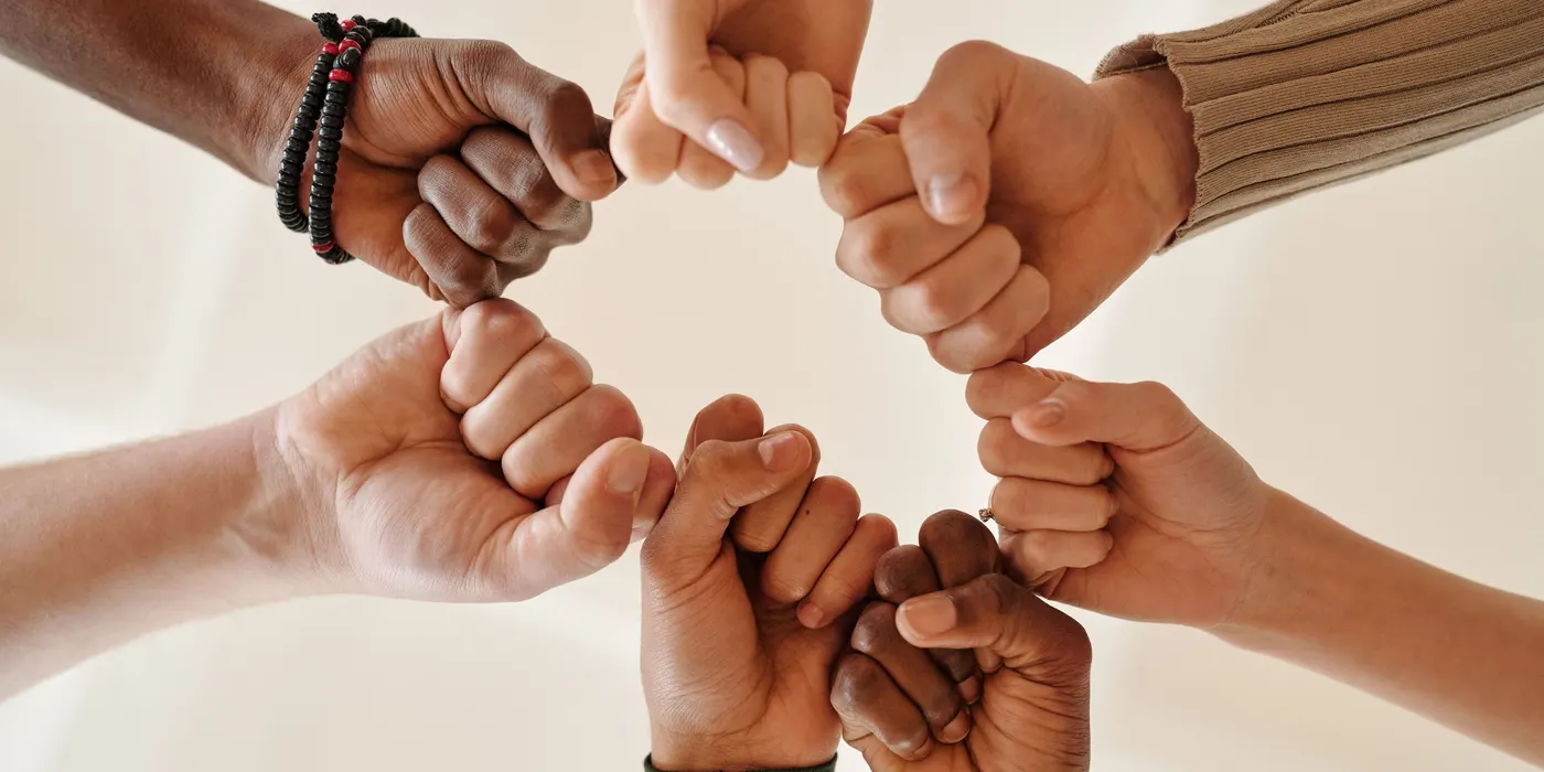 Hands of different people joined in a ring, fist to fist